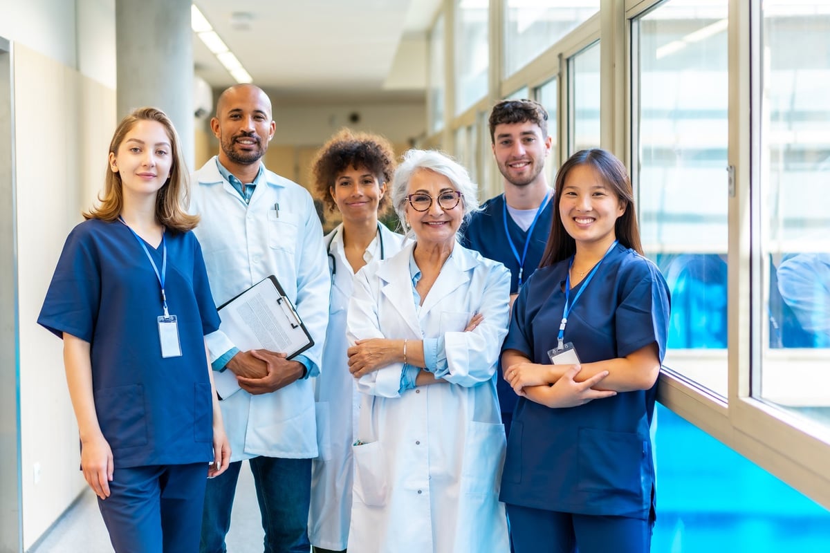 Equipo médico profesional y diverso sonriendo con confianza en un pasillo de hospital moderno