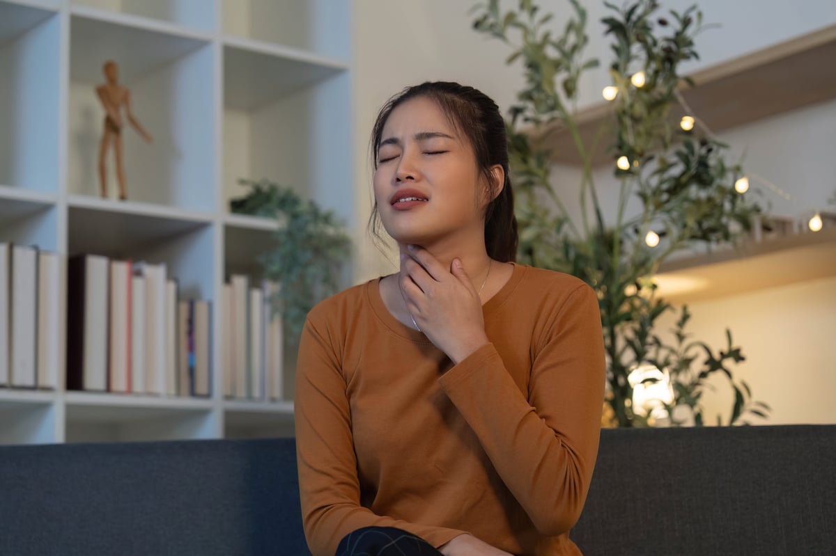 Mulher tocando a garganta mostrando desconforto